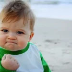 Baby clenching fist on sandy beach